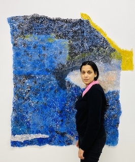 Portrait photo of artist Neha Vedpathak posing with her artwork